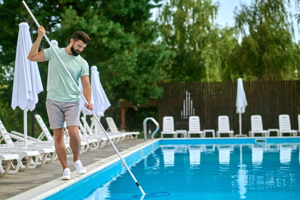 a-service-person-cleaning-the-swimming-pool-and-looking-busy.jpg - Bliss Pools